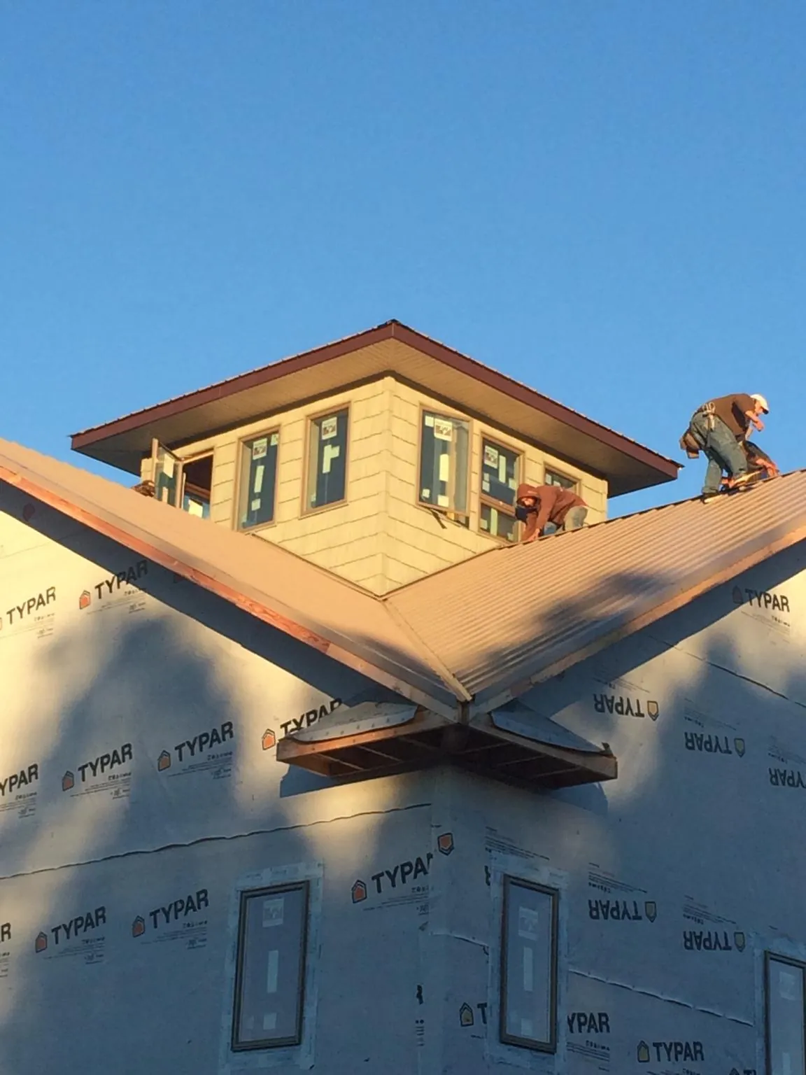Roofers working around a rooftop cupola on a new metal roof at sunset — Roof Waterproofing in Melrose by Roofing Brothers